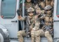Soldiers are sitting in a helicopter doorway.