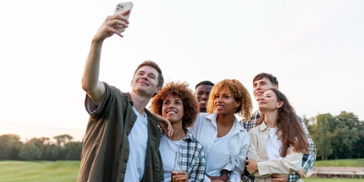 group of multiracial young people take selfies on smartphone and take picture